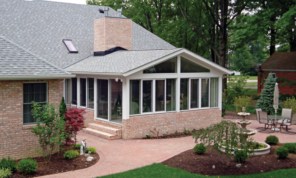 Brick home remodel in Cleveland featuring a large sunroom addition with energy-efficient windows and a landscaped patio area