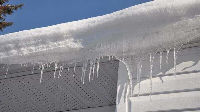 Man maintaining his gutters during winter season